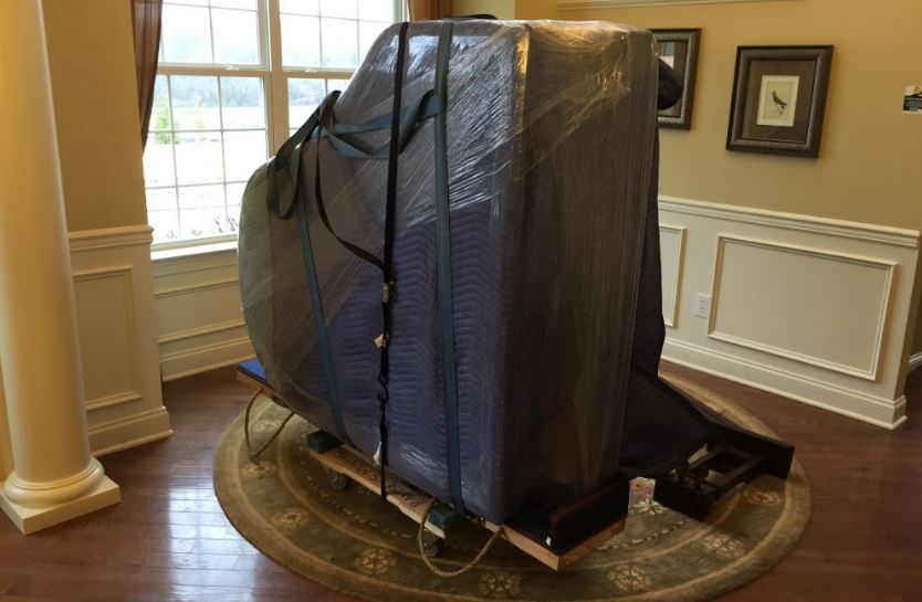 Professional piano movers team in Sarasota, Florida carefully moving a grand piano